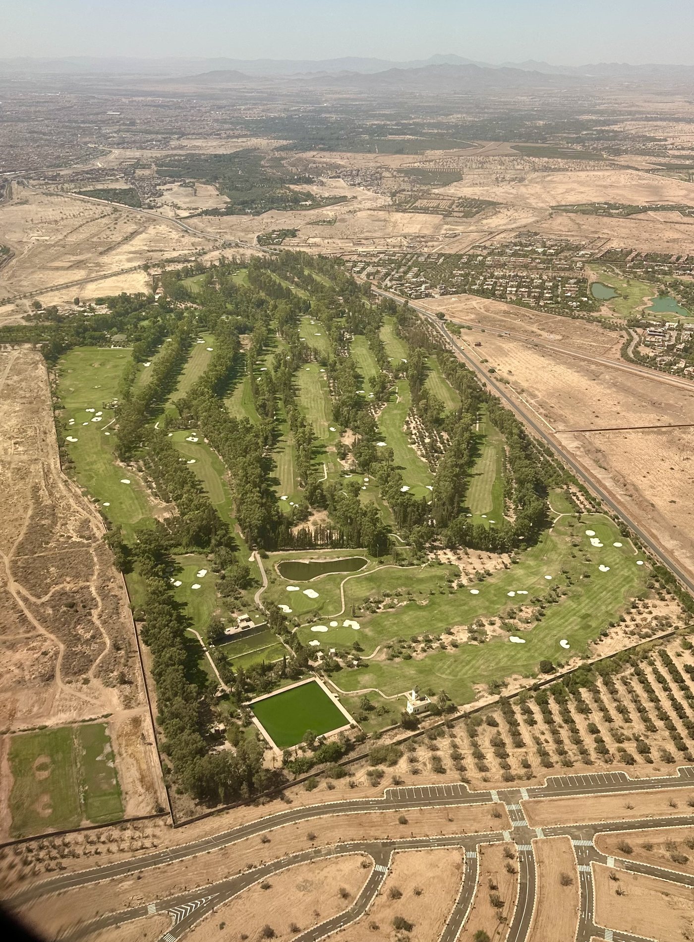 Vue aérienne verticale du Royal Golf Marrakech : les fairways s'étirent entre les oliveraies et les chemins de terre, jusqu'à l'horizon.
